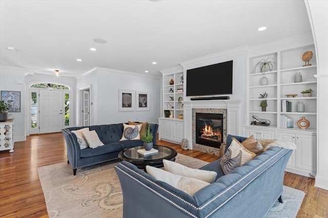 living room with crown molding, built in features, and light wood-type flooring