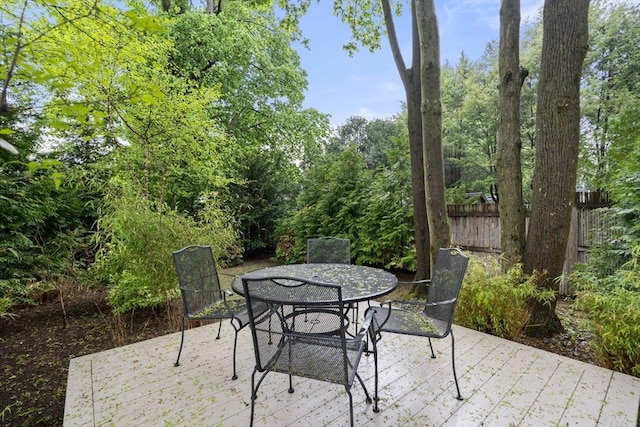 view of patio featuring fence, outdoor dining area, and a wooden deck