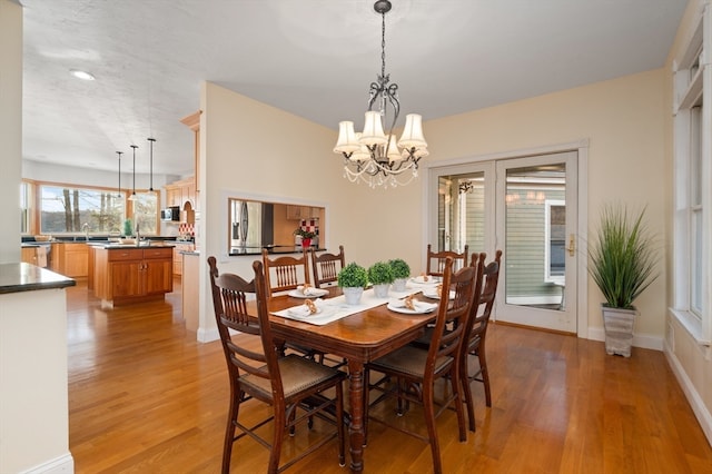 dining room with sink, light hardwood / wood-style flooring, and a notable chandelier