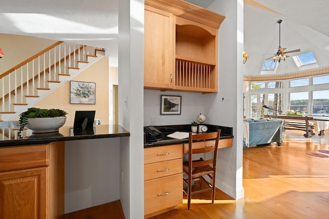 interior space with a skylight, ceiling fan, light brown cabinets, hardwood / wood-style flooring, and high vaulted ceiling