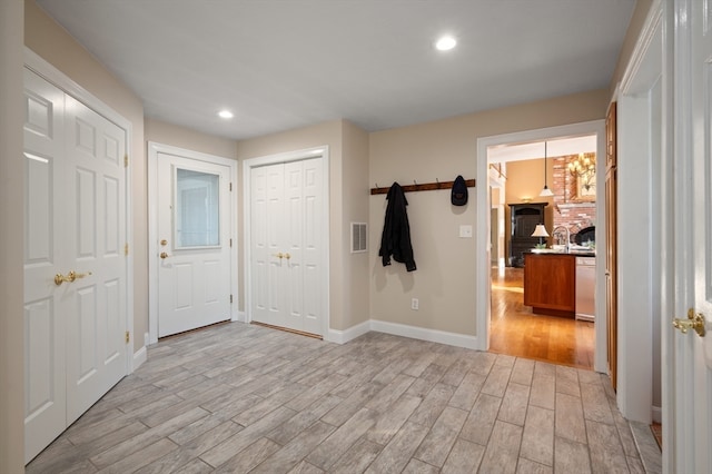 entrance foyer with light hardwood / wood-style flooring and a brick fireplace