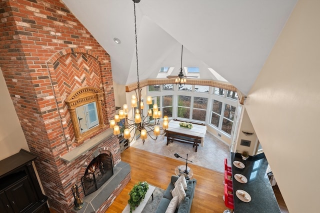 living room with a fireplace, wood-type flooring, ceiling fan with notable chandelier, and high vaulted ceiling