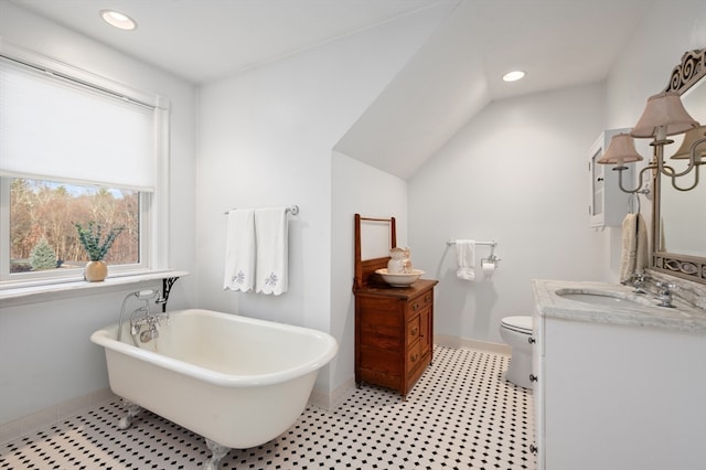 bathroom featuring a bathtub, toilet, lofted ceiling, and vanity