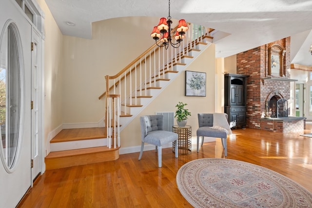 foyer with a chandelier, a textured ceiling, hardwood / wood-style flooring, and a fireplace