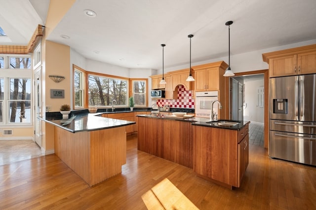 kitchen featuring hanging light fixtures, an island with sink, stainless steel appliances, and sink