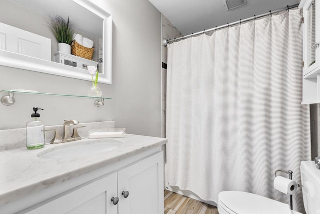full bath with visible vents, vanity, wood finished floors, toilet, and shower / tub combo