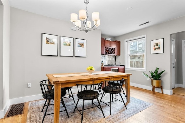 dining area with light wood-style floors, baseboards, a chandelier, and visible vents