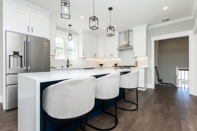 kitchen featuring high end refrigerator, light countertops, a kitchen island, and wall chimney exhaust hood