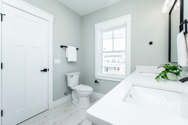 full bath featuring baseboards, a sink, a healthy amount of sunlight, and toilet