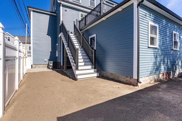view of side of home featuring fence and stairs
