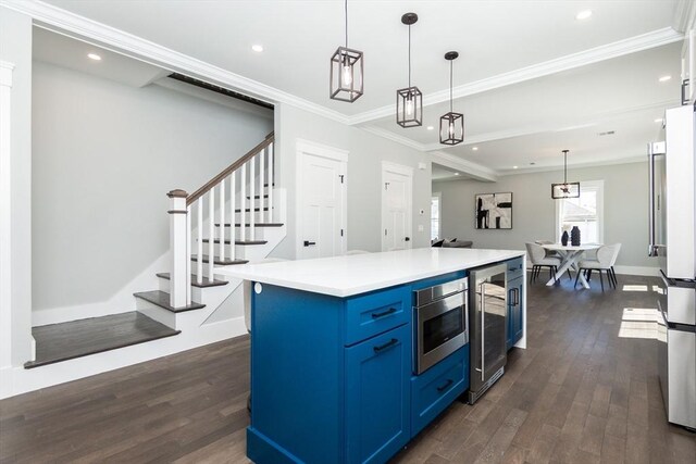 kitchen with appliances with stainless steel finishes, beverage cooler, blue cabinetry, and dark wood finished floors