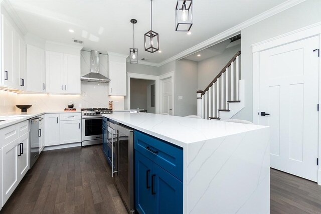 kitchen with wall chimney range hood, beverage cooler, stainless steel appliances, a kitchen island, and dark wood-style floors