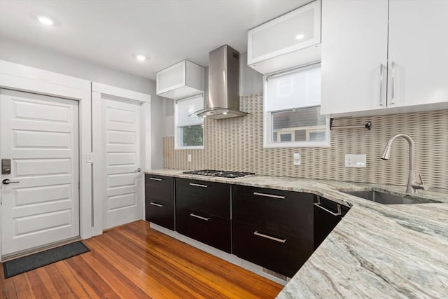 117 Sycamore St Unit 1, Boston, MA 02131 - kitchen with wall chimney exhaust hood, a sink, stainless steel gas cooktop, wood finished floors, and light stone counters
