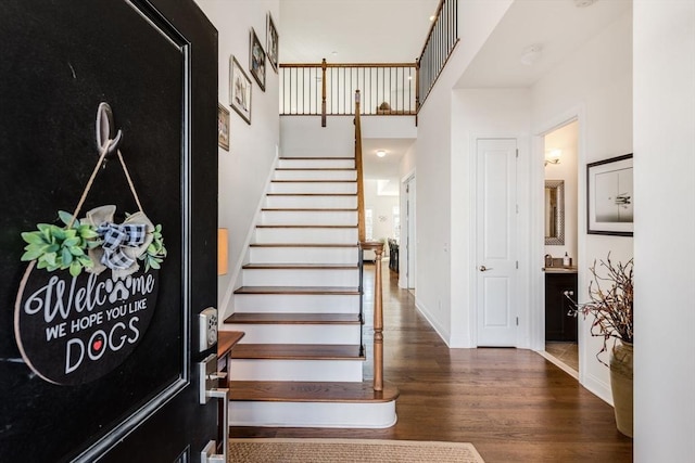 foyer featuring stairs, a high ceiling, wood finished floors, and baseboards