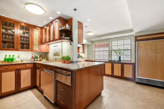 kitchen featuring light stone countertops, kitchen peninsula, and sink