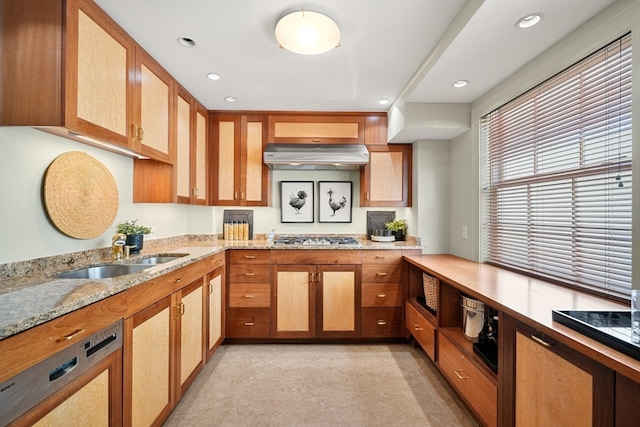 kitchen with appliances with stainless steel finishes, light stone counters, and sink