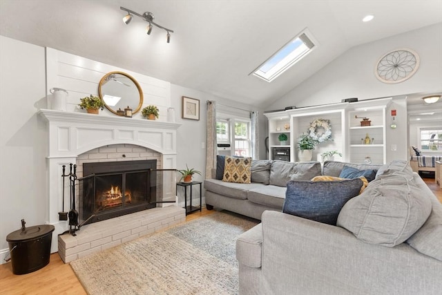 25 12th Ave, Halifax, MA 02338 - living room with light wood finished floors, vaulted ceiling, a brick fireplace, a skylight, and healthy amount of natural light
