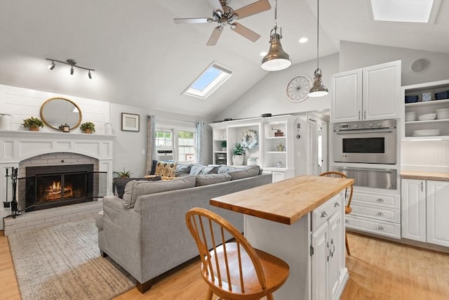 25 12th Ave, Halifax, MA 02338 - living room with a skylight, light wood-style flooring, a ceiling fan, a fireplace, and high vaulted ceiling