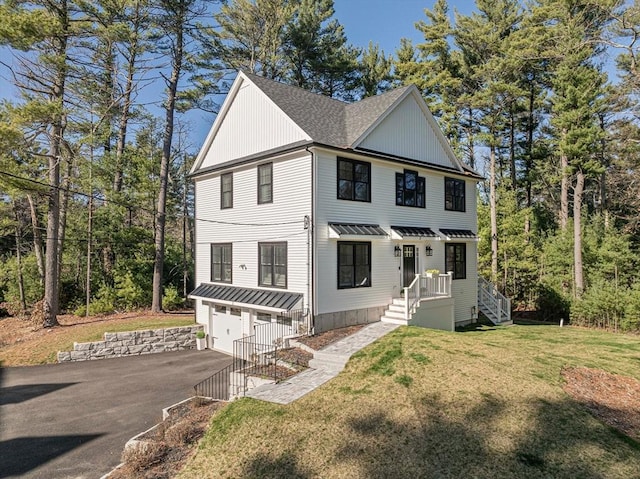 view of front facade with a standing seam roof, driveway, a front yard, a garage, and a shingled roof