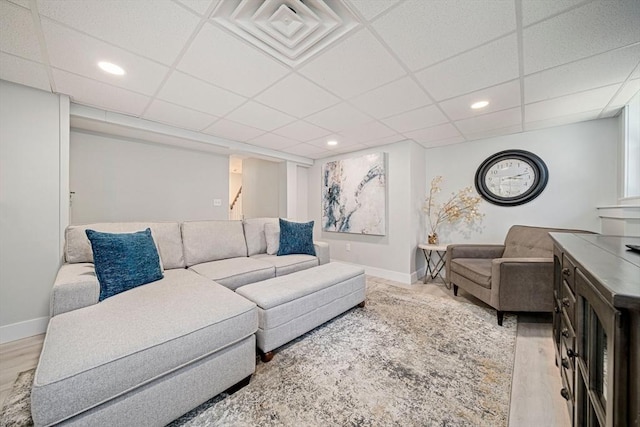 living area featuring baseboards, visible vents, a drop ceiling, and wood finished floors