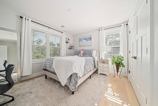 bedroom featuring baseboards, light wood finished floors, and visible vents