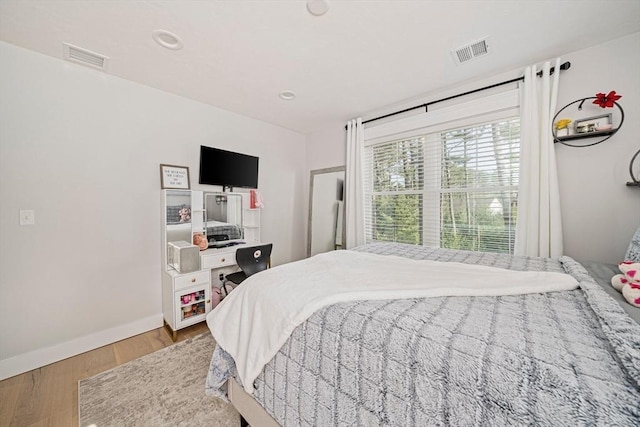 bedroom featuring visible vents, baseboards, and wood finished floors