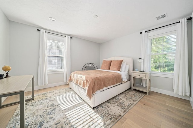 bedroom with baseboards, light wood-type flooring, and visible vents
