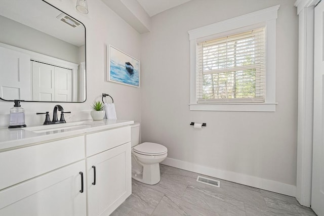 bathroom featuring vanity, toilet, marble finish floor, baseboards, and visible vents