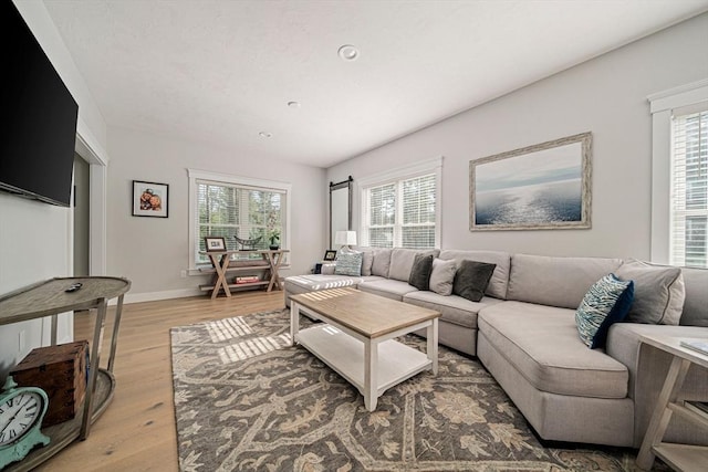 living room with light wood-type flooring, recessed lighting, baseboards, and plenty of natural light