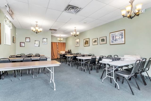 dining area with a notable chandelier, carpet flooring, and a paneled ceiling