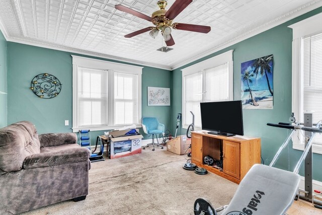 carpeted living room with ornamental molding and ceiling fan