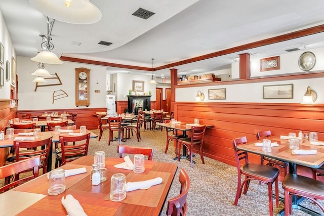 carpeted dining space with wood walls