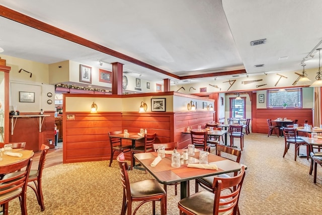 dining room featuring wooden walls, light colored carpet, and rail lighting