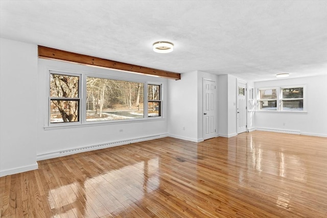 260 Great Rd, Stow, MA 01775 - unfurnished living room featuring baseboard heating, a textured ceiling, wood-type flooring, and baseboards
