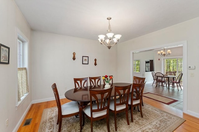dining room with a chandelier, light wood finished floors, and baseboards