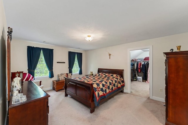 bedroom with light carpet, a walk in closet, and baseboards