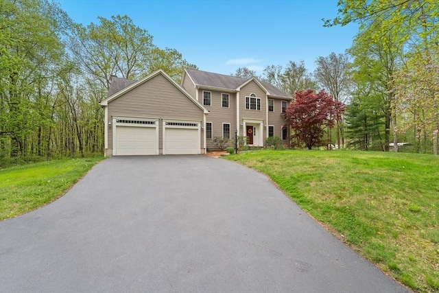 colonial inspired home featuring asphalt driveway, a front lawn, and a garage