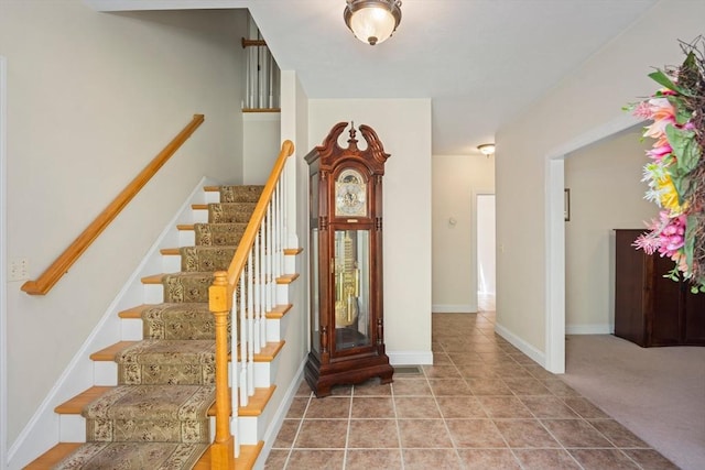 foyer entrance with stairs and baseboards