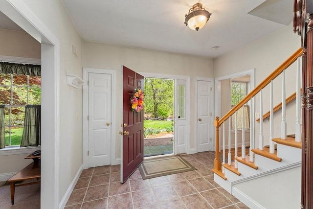 tiled foyer with healthy amount of natural light and stairs