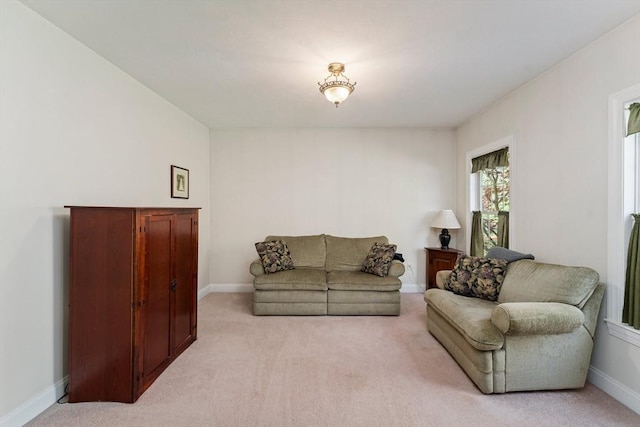 living area featuring light carpet and baseboards