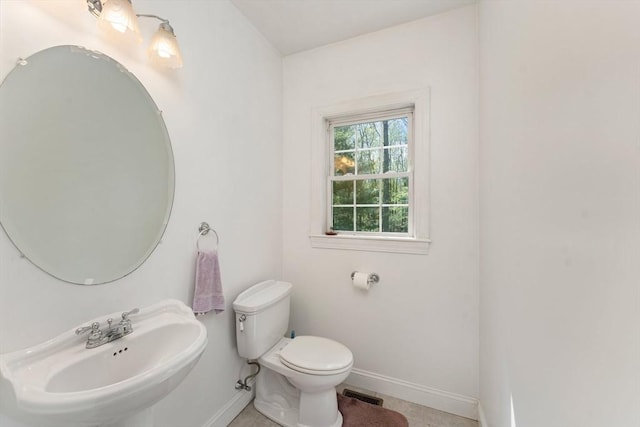 bathroom with baseboards, a sink, and toilet