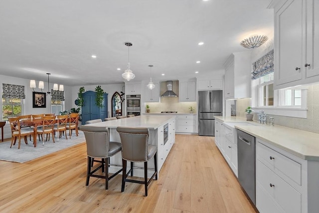 124 Osgood Rd, Charlton, MA 01507 - kitchen with wall chimney range hood, stainless steel appliances, light wood finished floors, recessed lighting, and white cabinets