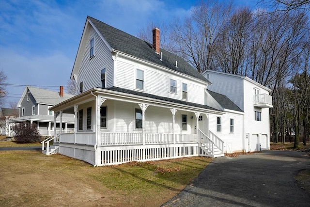 view of front of home featuring covered porch, a garage, and a front lawn