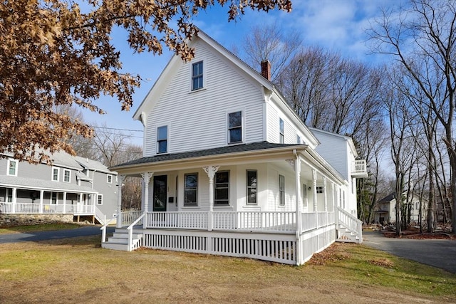 farmhouse featuring covered porch and a front yard