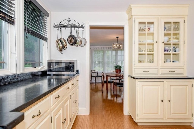 670 Front St, Marion, MA 02738 - kitchen featuring stainless steel microwave, light wood-style floors, a chandelier, and dark countertops