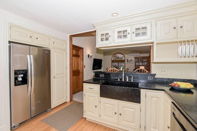 670 Front St, Marion, MA 02738 - kitchen featuring appliances with stainless steel finishes, dark countertops, cream cabinets, light wood-style flooring, and glass insert cabinets