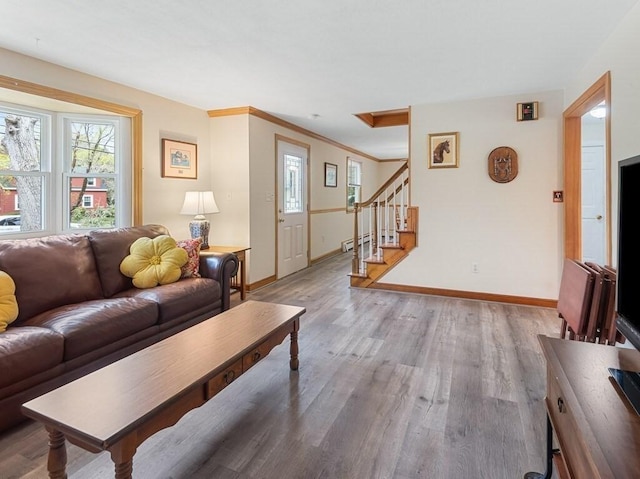 living area with baseboards, wood finished floors, and stairway