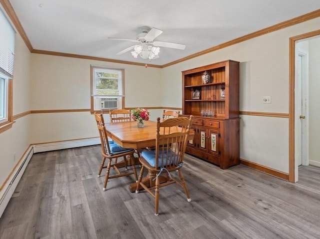 dining area featuring crown molding, a ceiling fan, a baseboard heating unit, and wood finished floors
