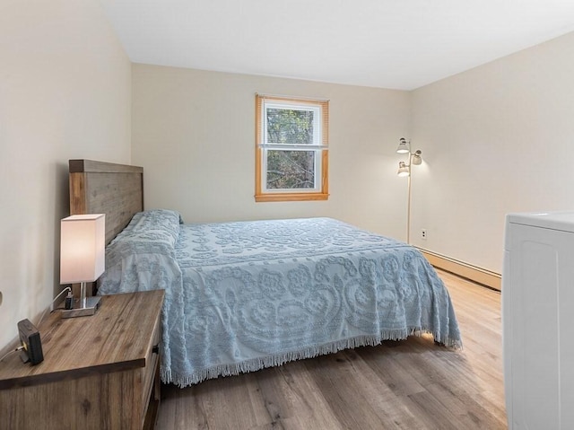 bedroom with a baseboard heating unit and wood finished floors