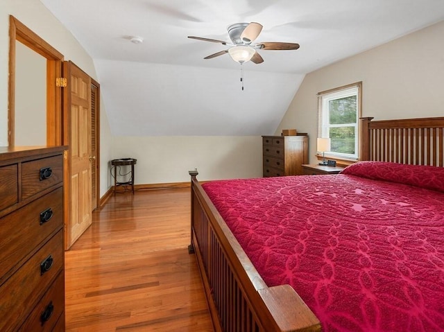 bedroom with baseboards, ceiling fan, light wood-style flooring, and lofted ceiling